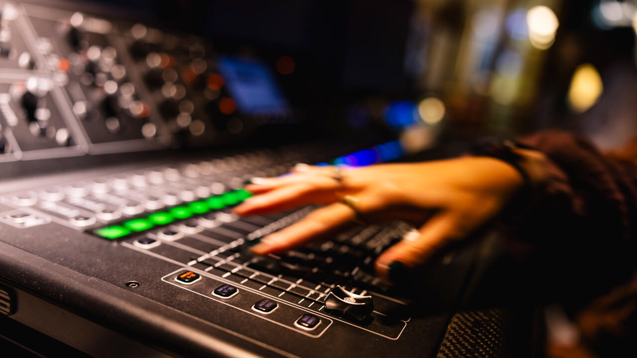 Hand turning up audio in the McMahon Center control room.