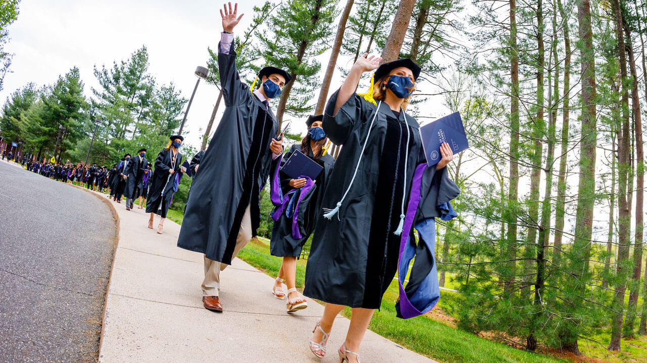 Graduates walk in a line toward the quad for the ceremony