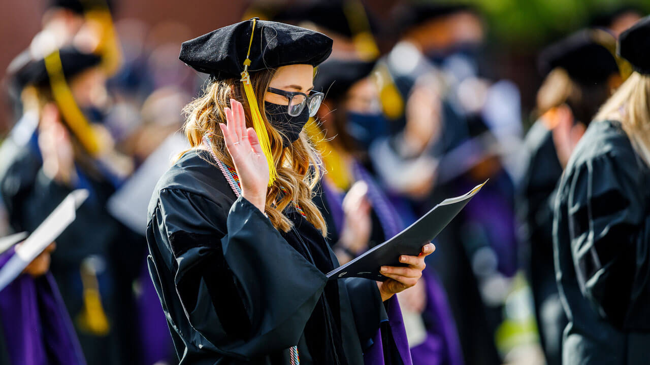 A graduate holds up her hand as she takes an oath