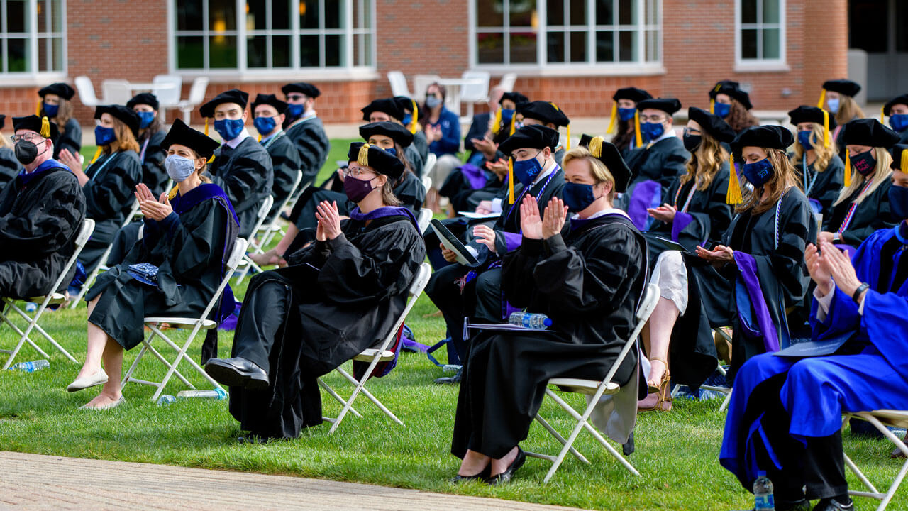 Rows of graduates and faculty clap during the ceremony