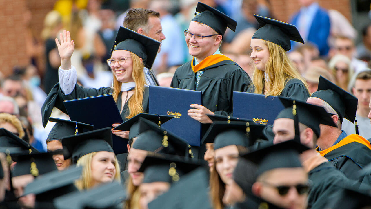 Graduate waving with her diploma