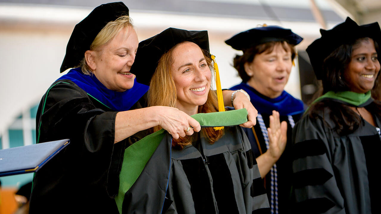 A graduate receives their hood on stage