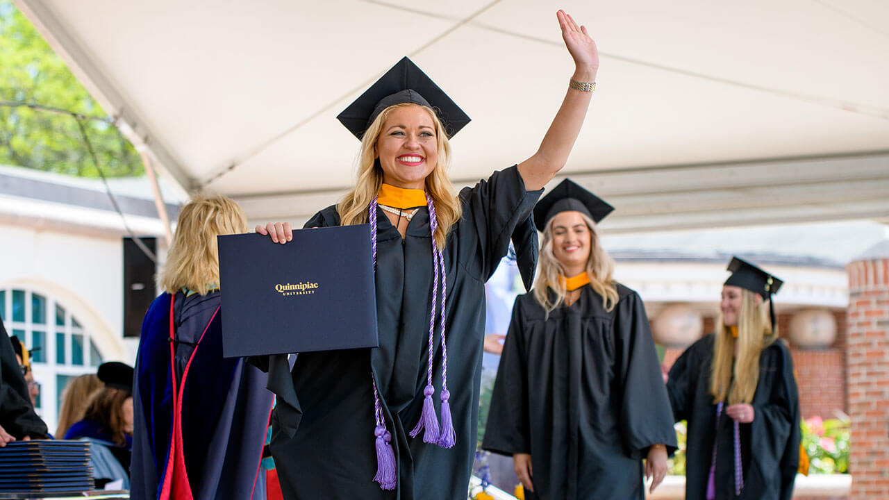 Graduate student holds up her diploma for a picture