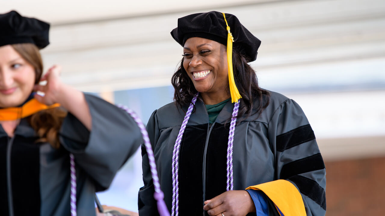 Graduate walking across the stage at Commencement with a smile on their face.