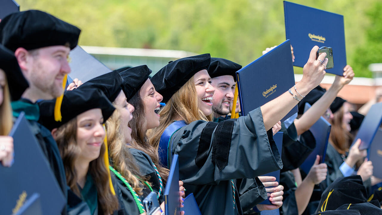 Graduate students laugh and smile as they stand