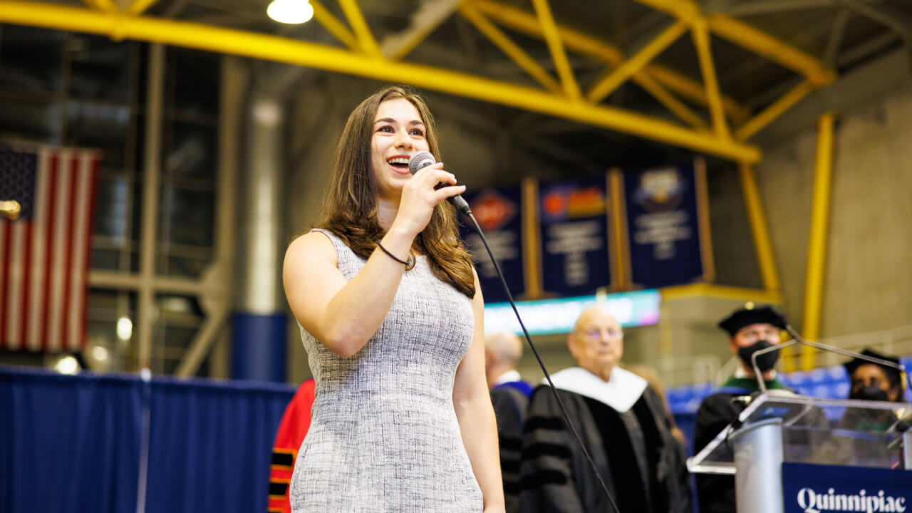 Anoush Calikyan sings the national anthem with a microphone on the stage