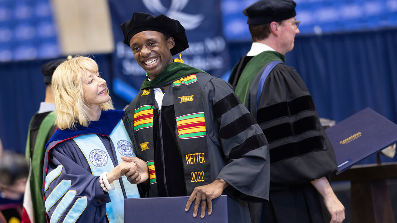 President Olian shakes hands with a medical graduate as he walks across the stage