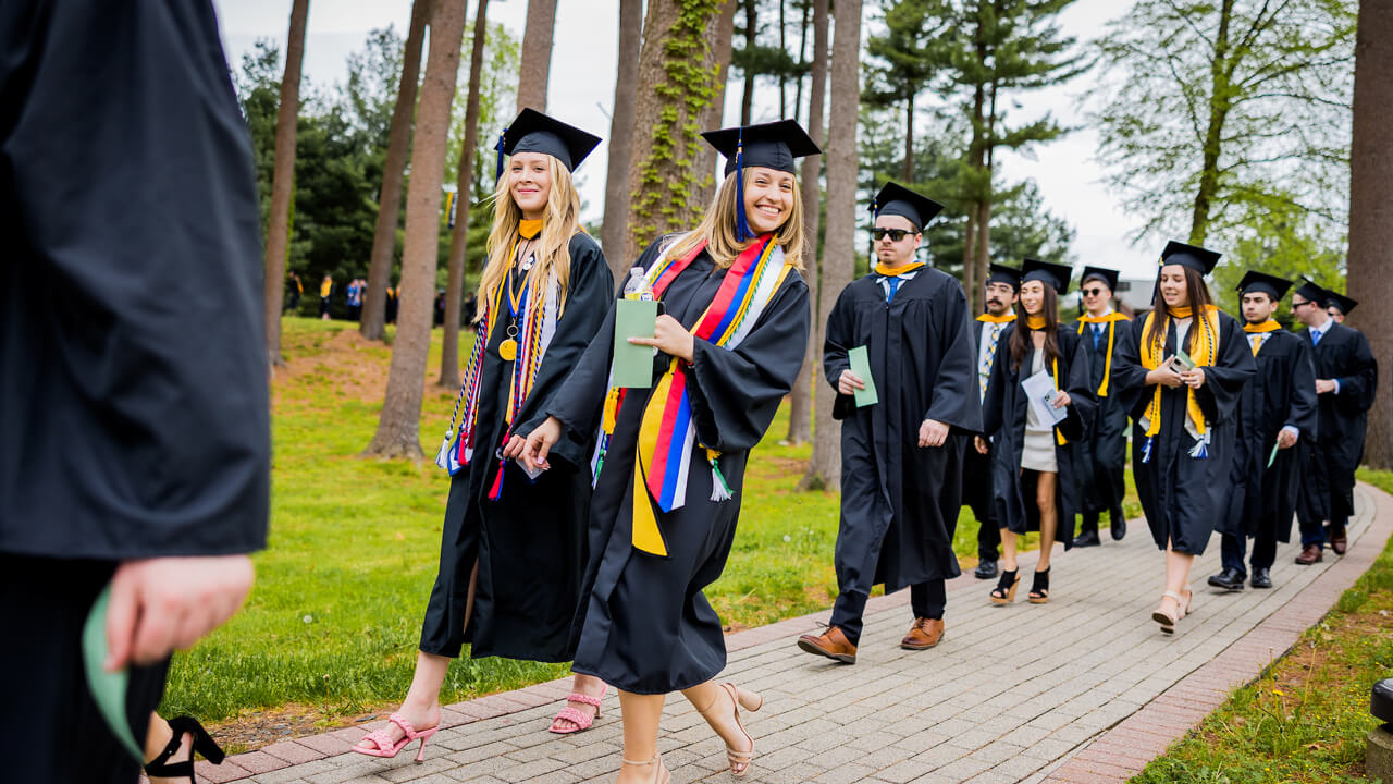 Two graduates smile at the camera during Processional