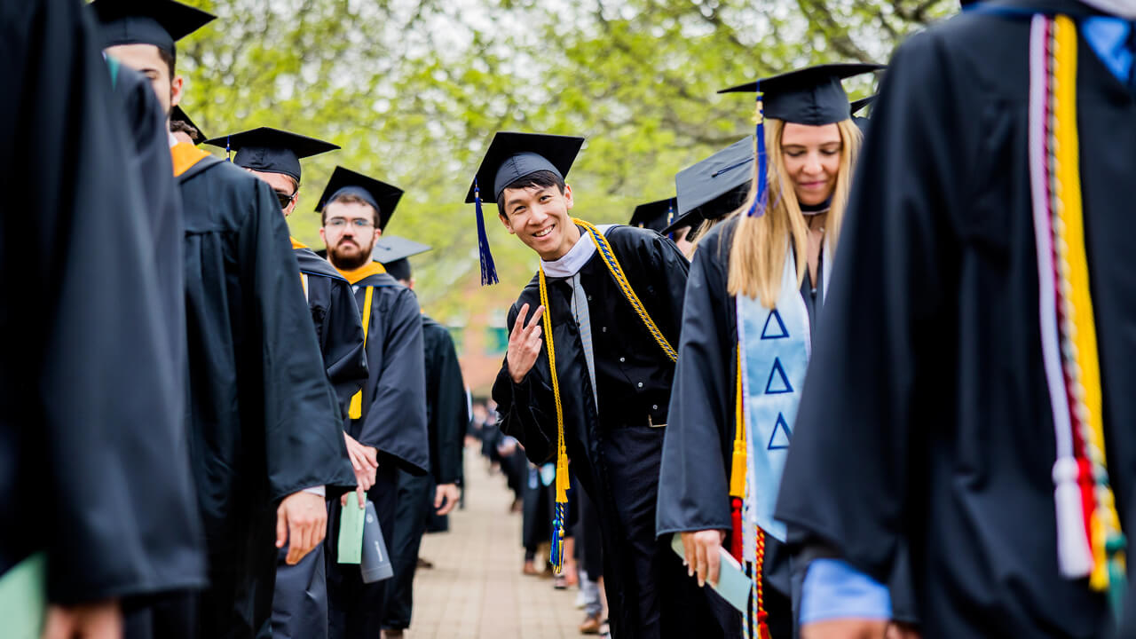 Graduate students line up and walk toward their seats