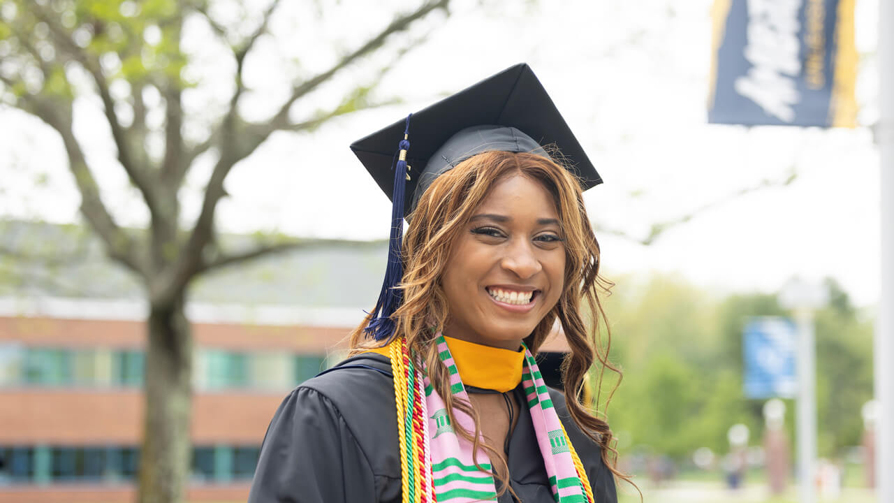 Graduate student smiles for a photo on the Quad