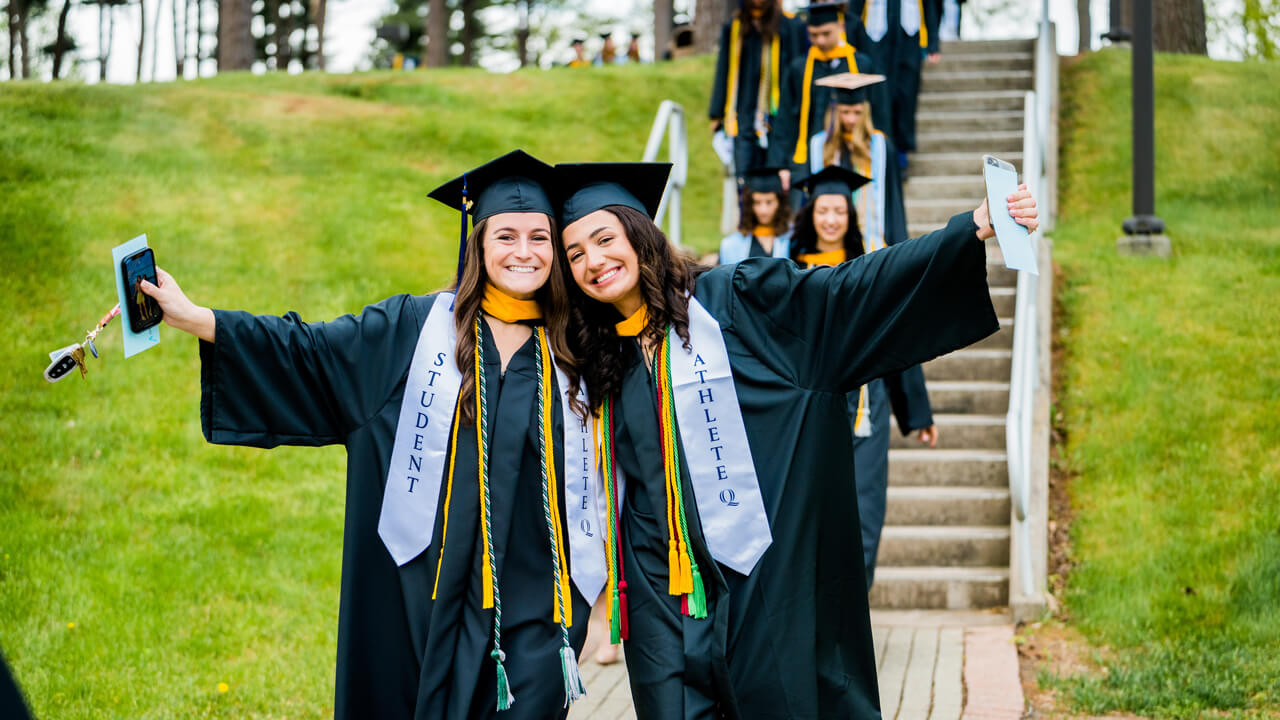 Two graduates embrace as they pose for a photo