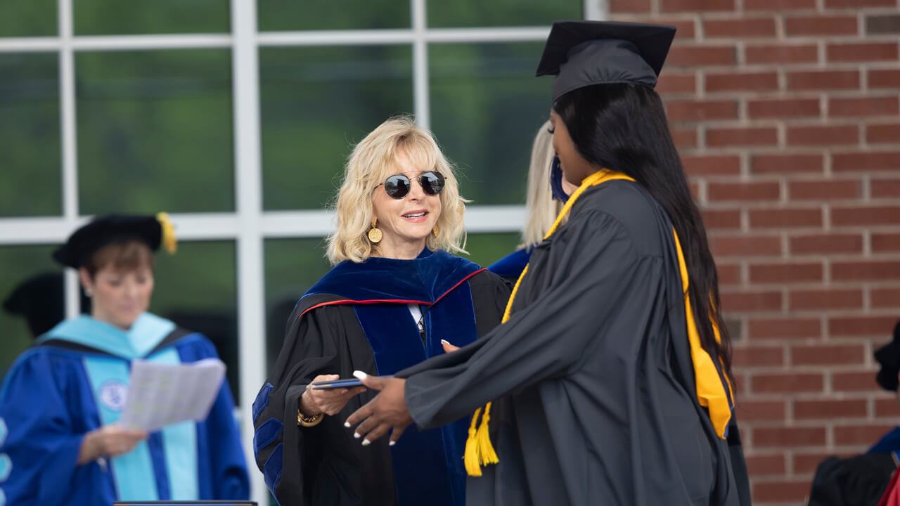 President Olian shakes hands with a new graduate onstage