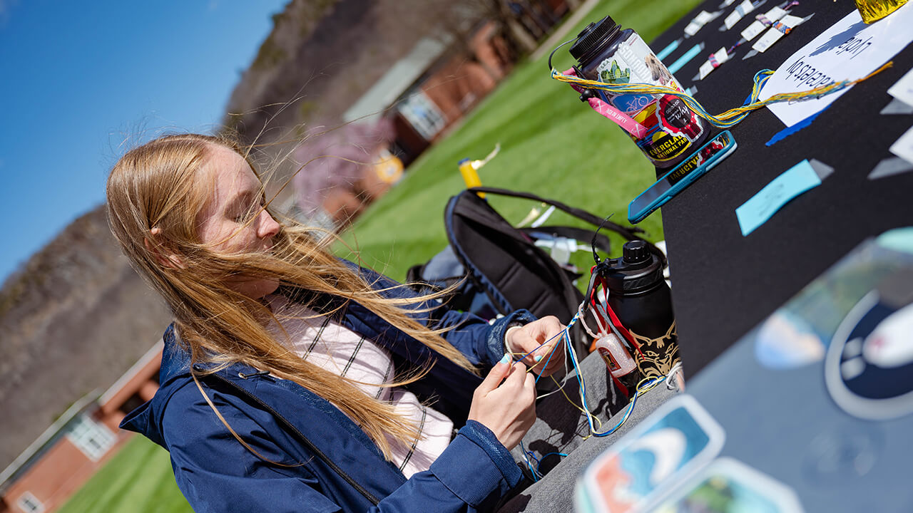 A student braids a bracelet.