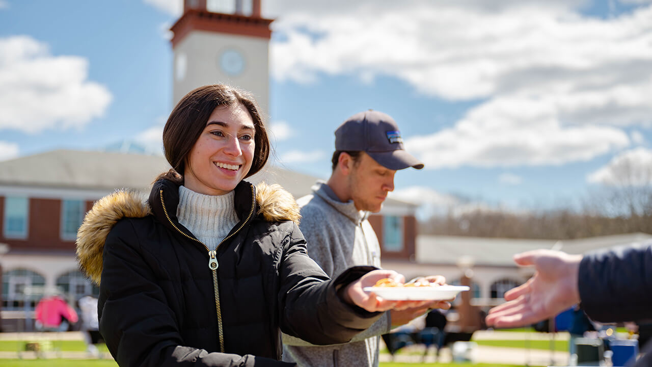 A student hands another student a plate of food.