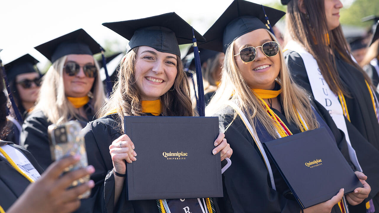 A student takes a picture with her cell phone while others smile