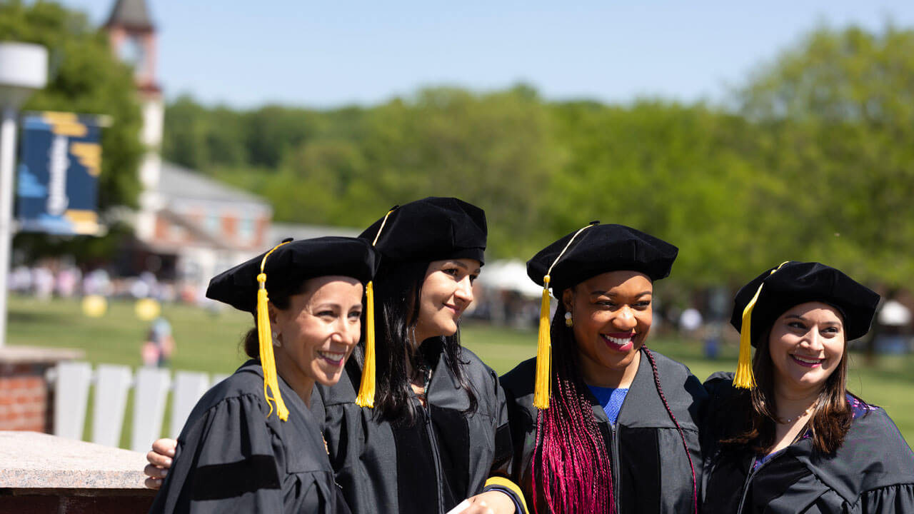 Four students stand shoulder to shoulder and pose for a photo together