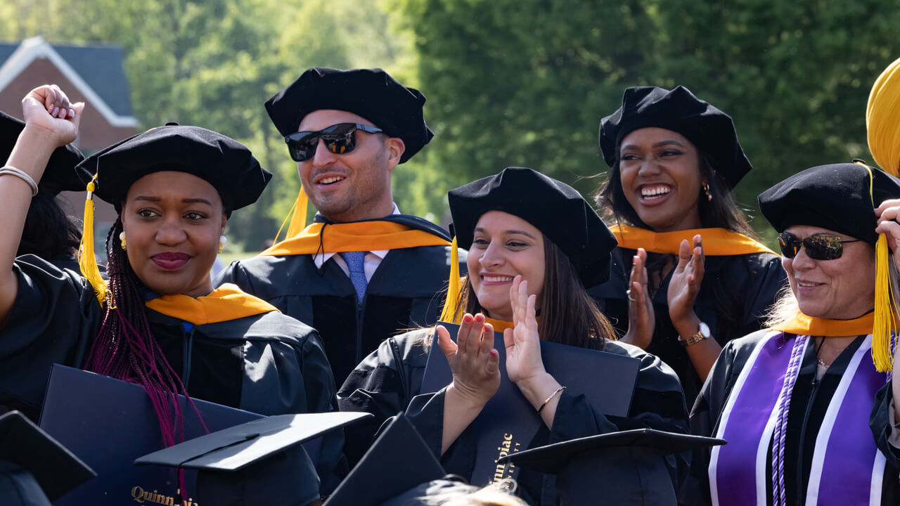 A group of doctoral nursing graduates clap and cheer