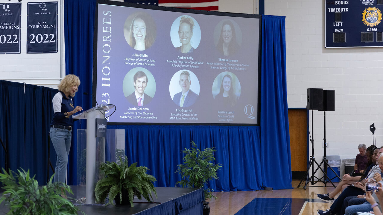 Judy Olian speaks at a podium with a screen showing the 2023 excellence honorees