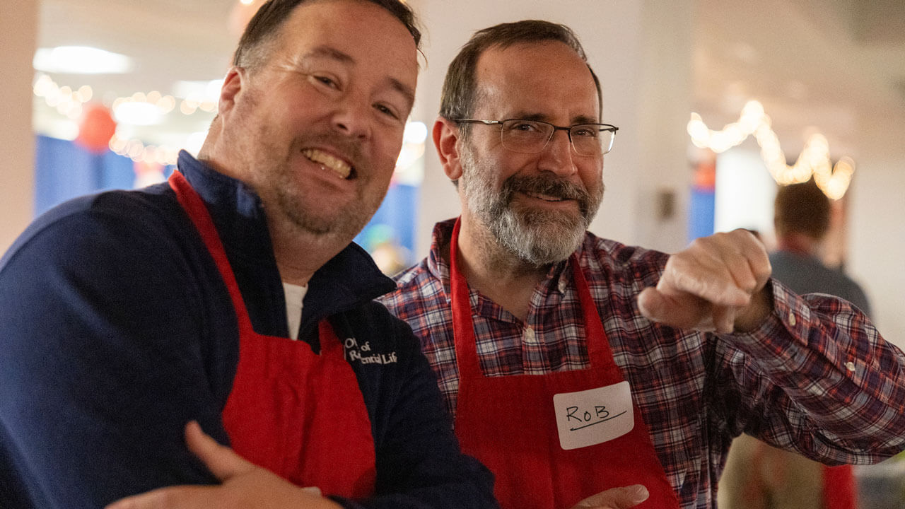 Two professors smile and pose for a photo together