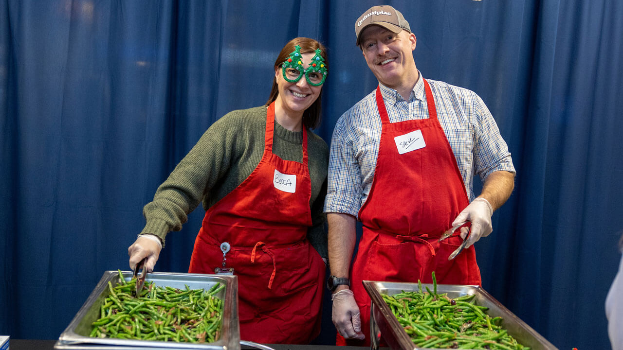 Two professors wear red aprons smiling together