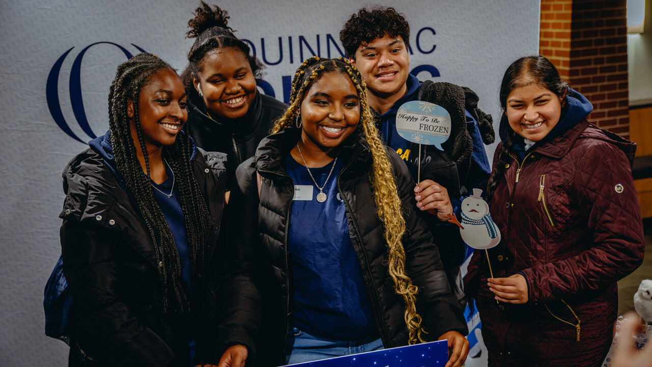 Group of students pose together for a photo holding up holiday decorations