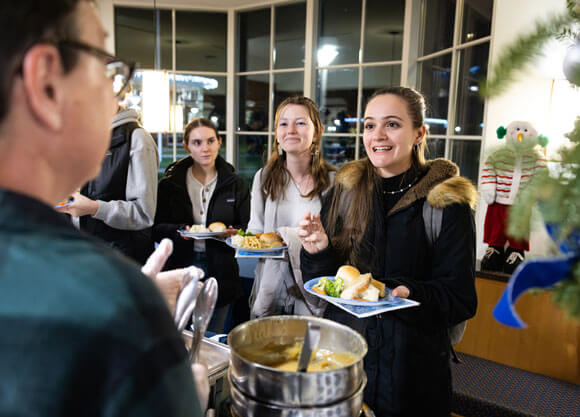 Student holds plate full of food as professor serves her