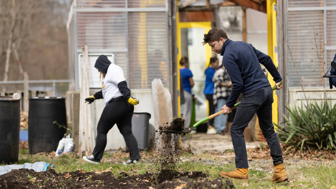 Student shovels dirt in garden