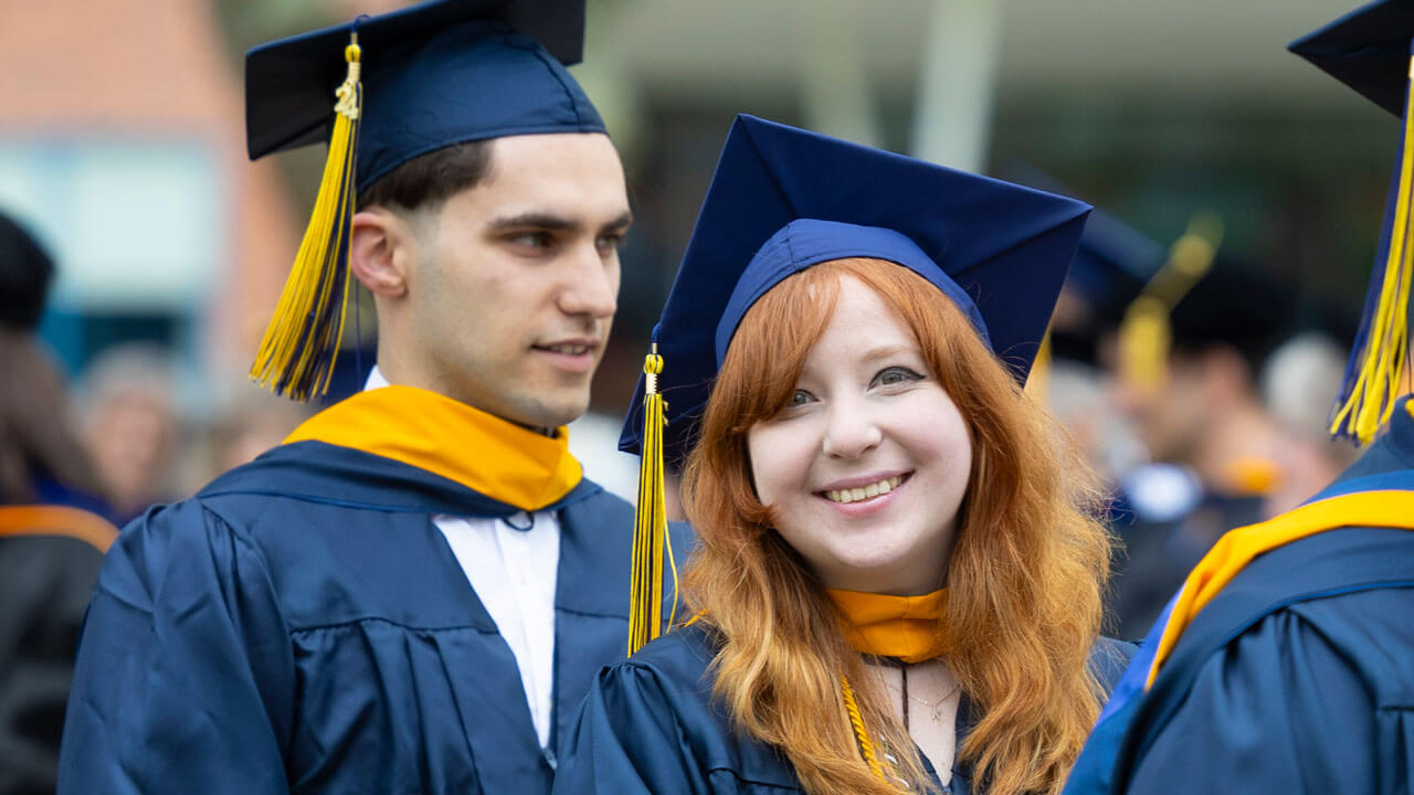 Graduates smiling and walking  in the CAS Commencement