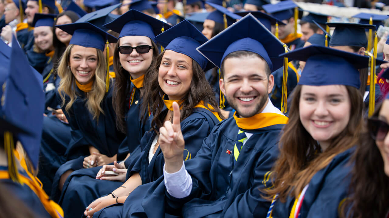 A row of graduates smile and pose for a photo