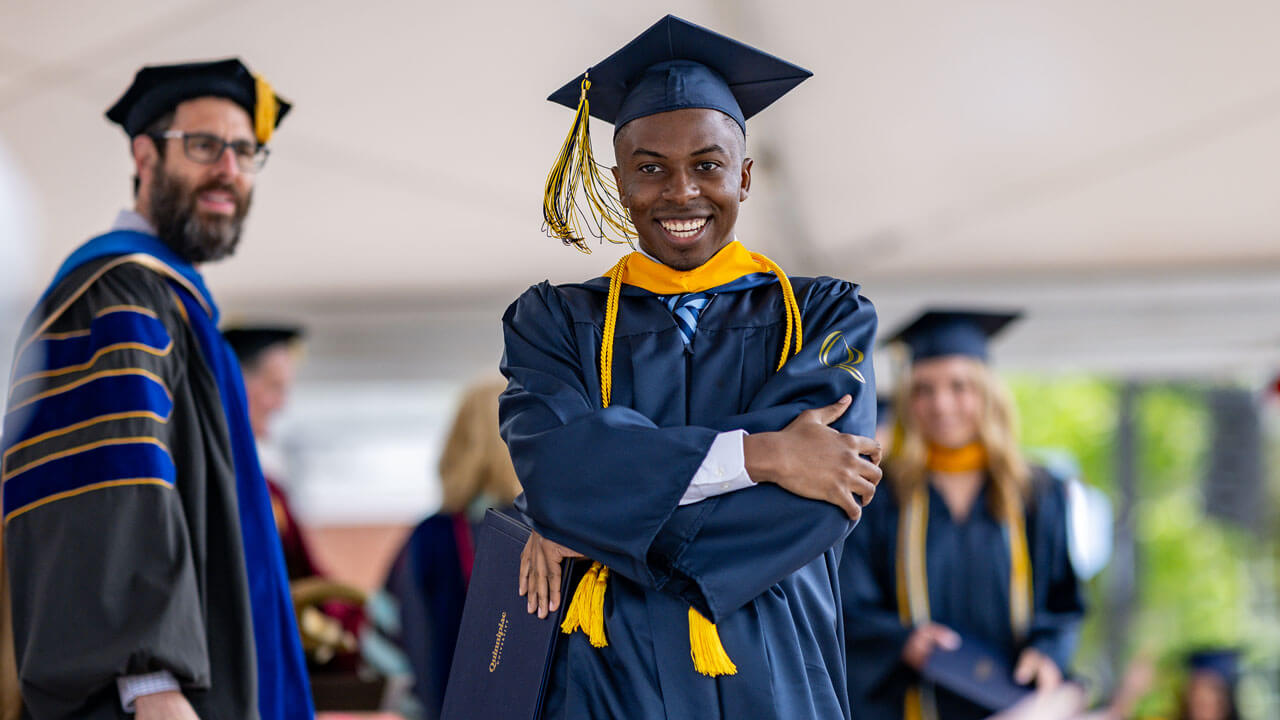 Graduate poses on stage holding his degree