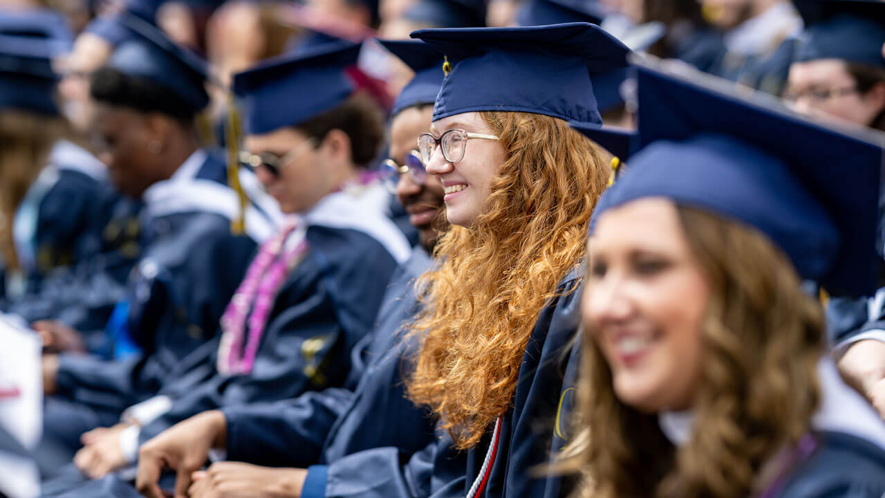 Quinnipiac OSC graduates seated and smiling towards the stage