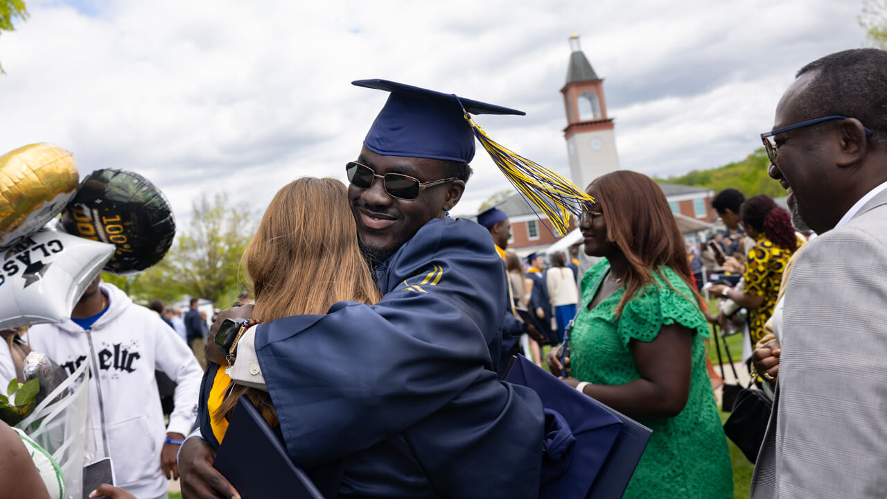 A graduate hugs his family member while she holds balloons