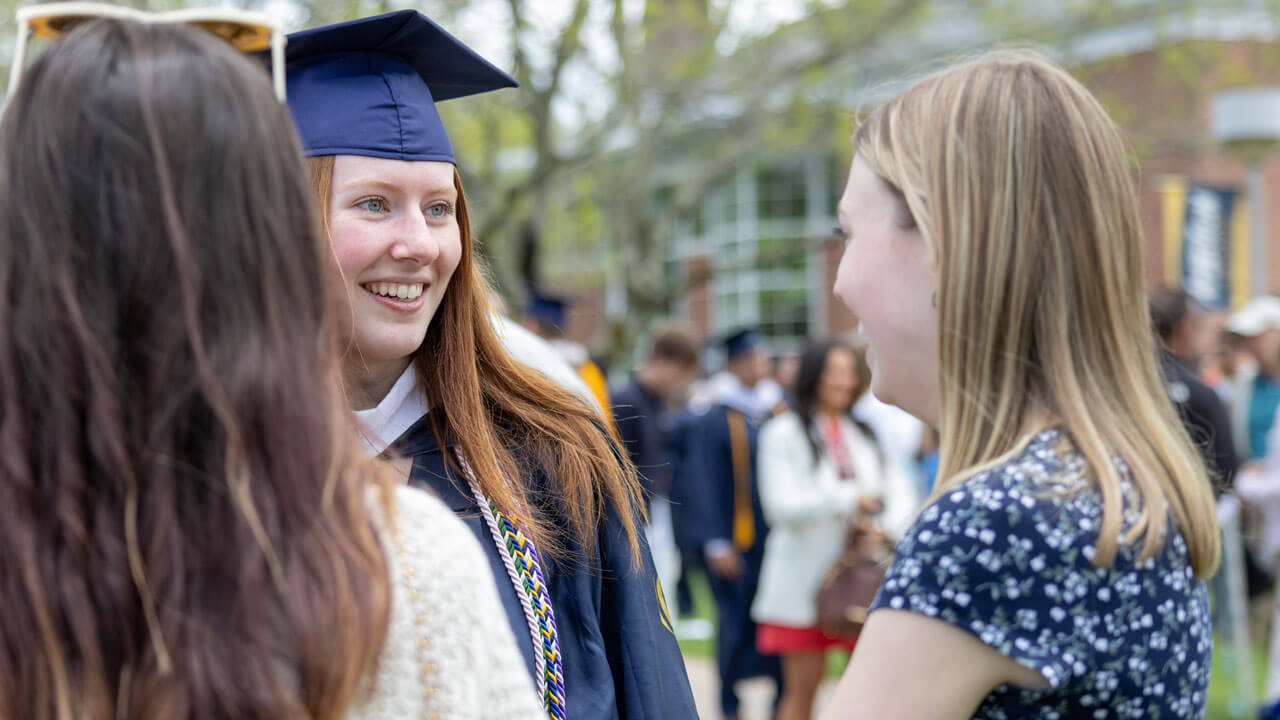 Graduate talks to her friends on the quad