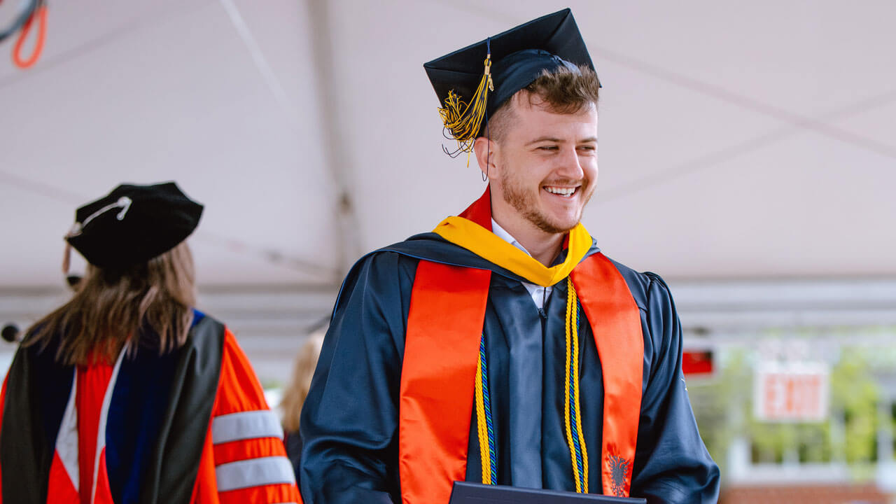 An elated Health Sciences graduate student smiles widely after being awarded with their diploma.