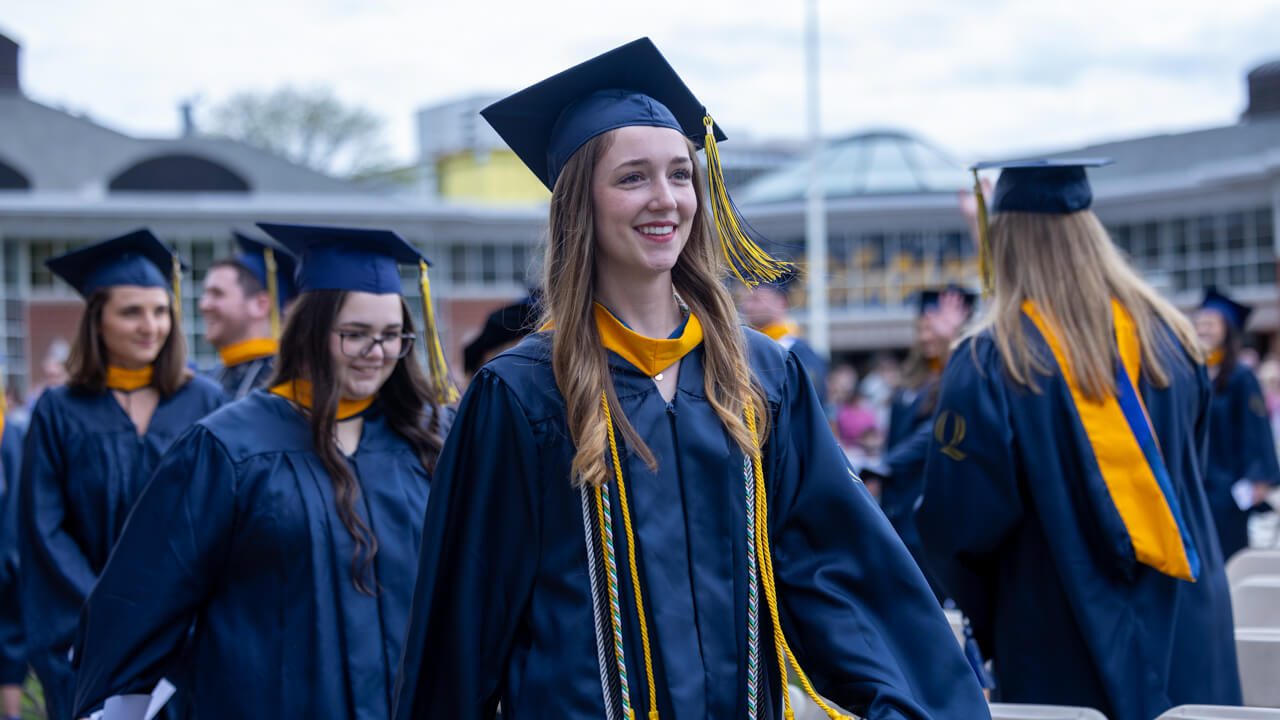 Several graduates walk by the student center as they smile