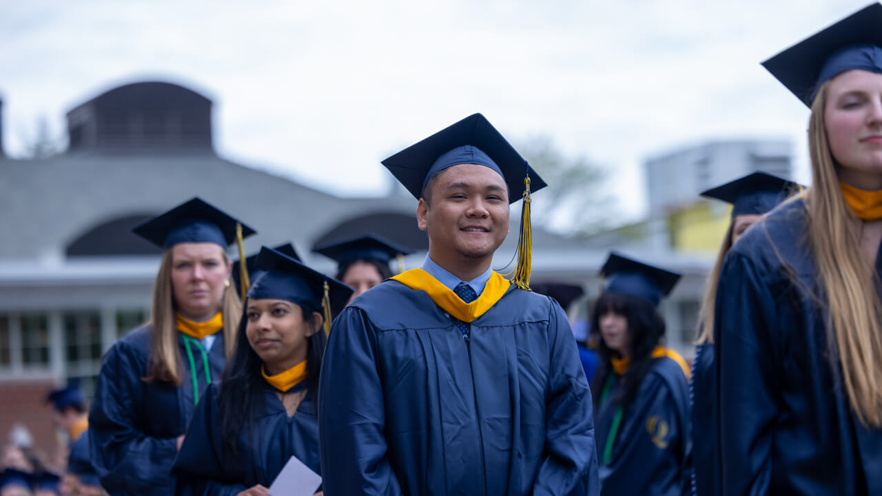 A handful of students smile as they walk across the quad