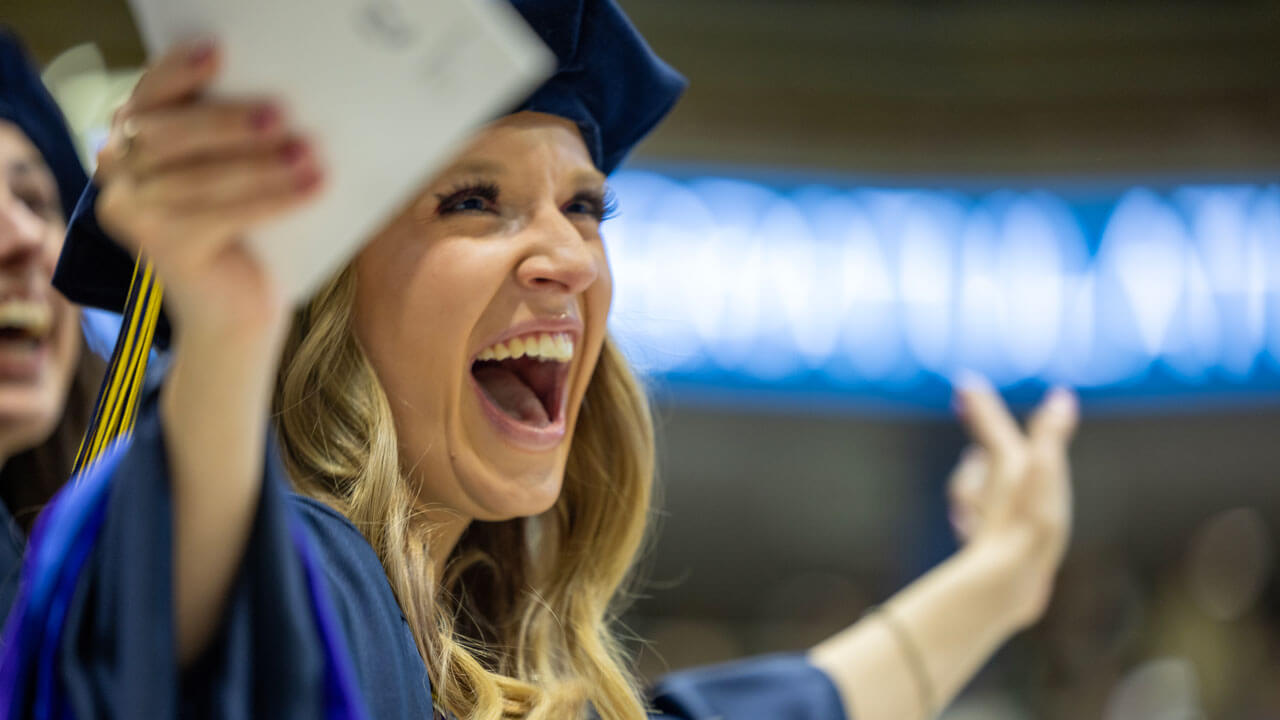 Class of 2024 law graduate shouts with enthusiasm during commencement ceremony.