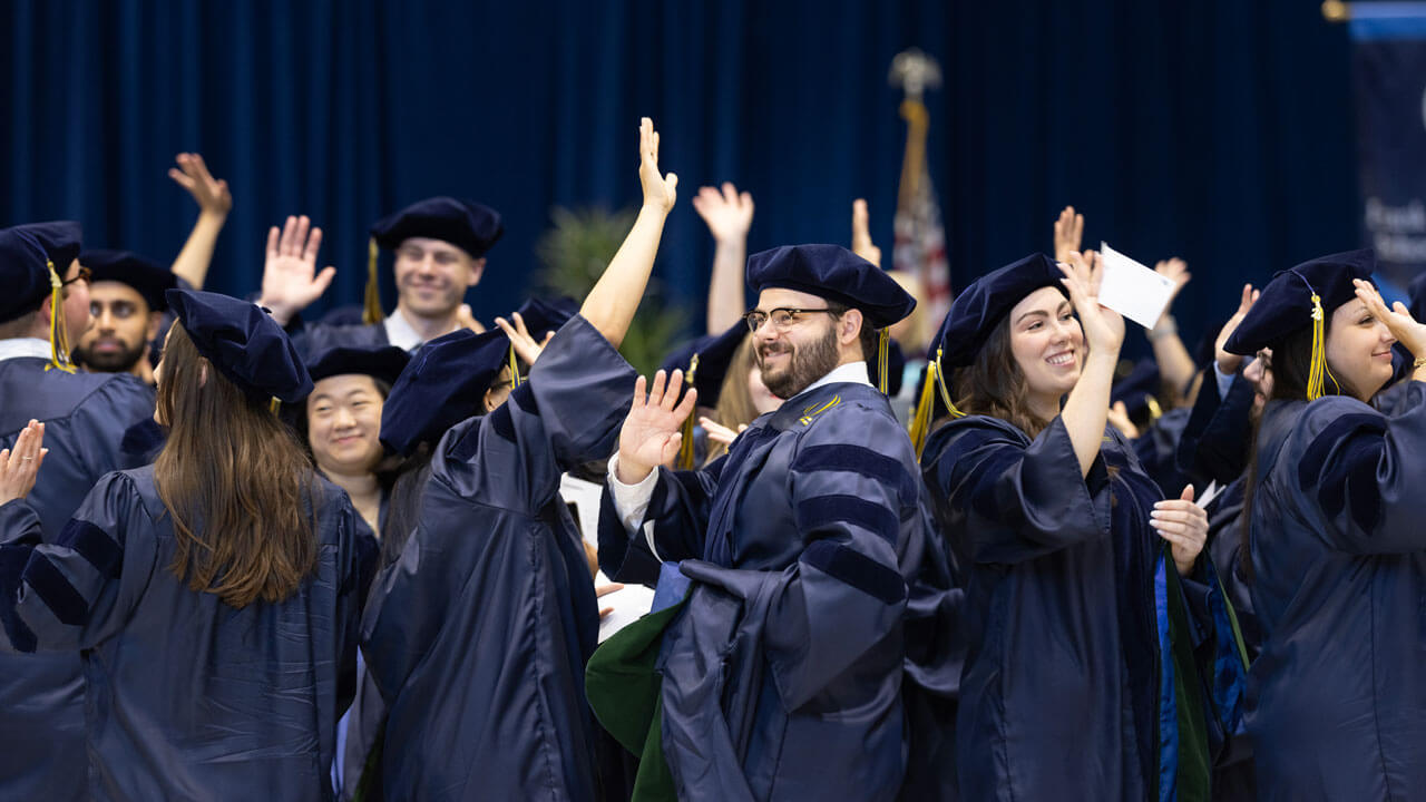 Group of School of Medicine students waving to the crowd smiling