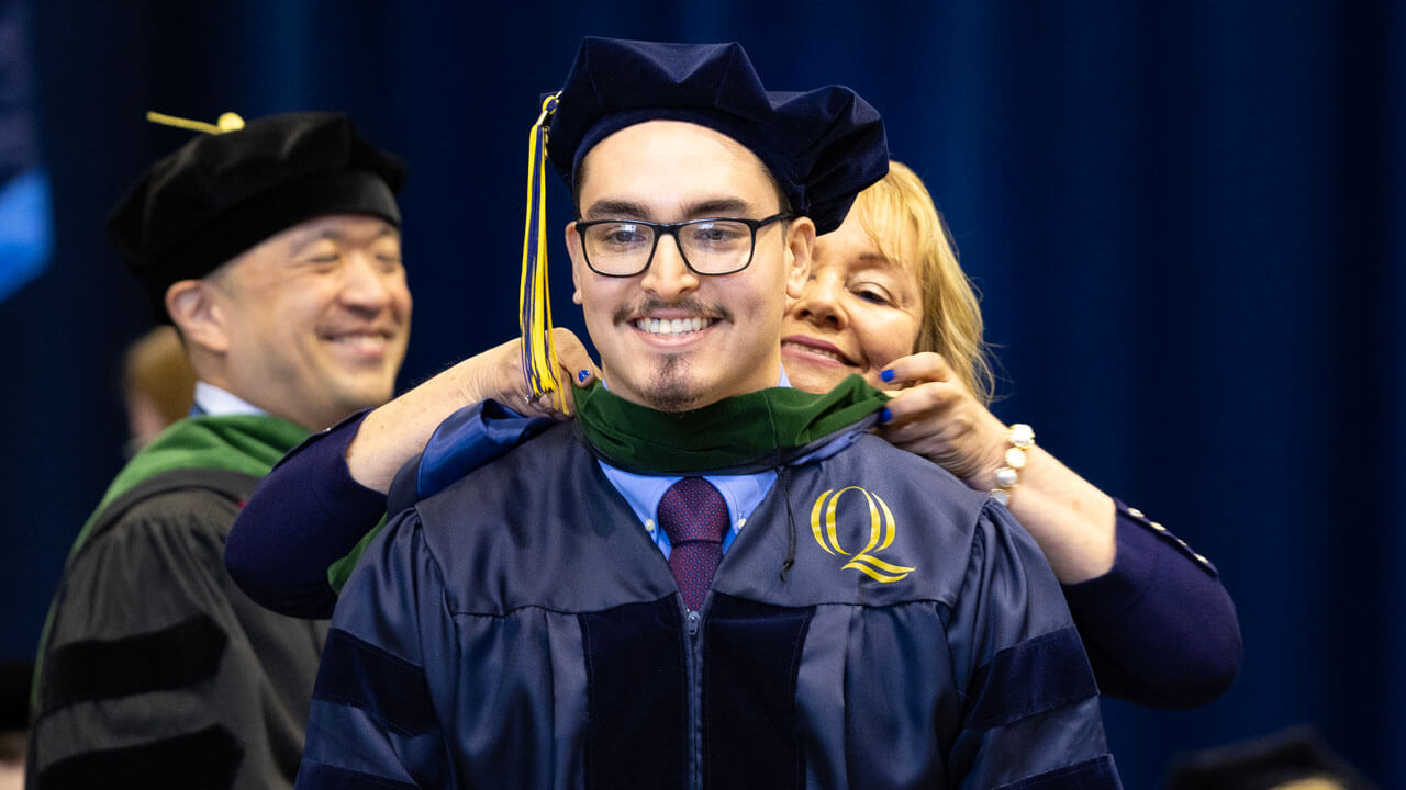 Medicine graduate hooded by family member during commencement