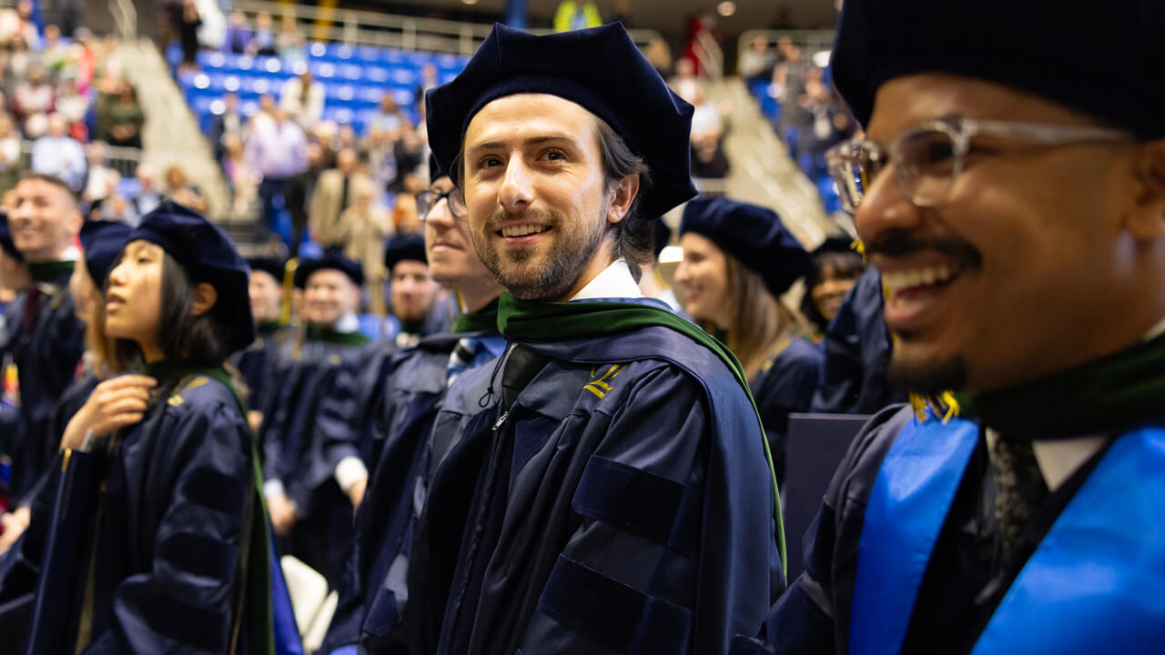 Graduates smile broadly as they sit in their seats during the Commencement ceremony