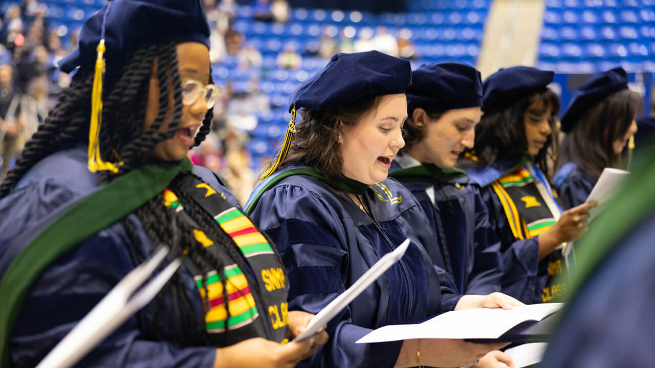 Graduates read from papers they hold as they recite the Hippocratic Oath