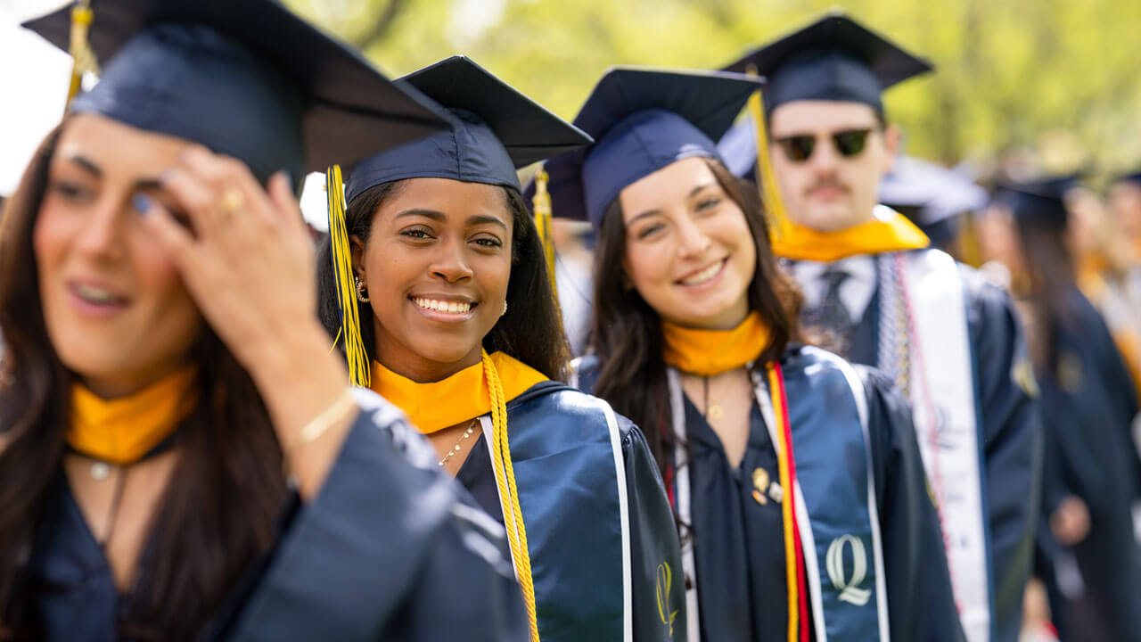 Graduate smiles for the photo as the sun shines down on the quad.