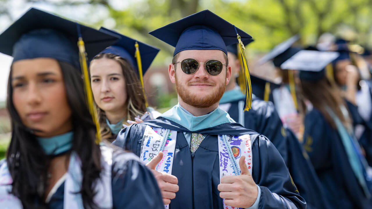 Class of 2024 School of Education graduate gives the camera two thumbs up.