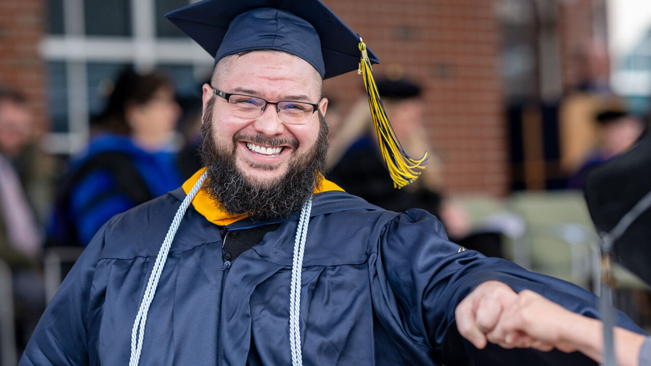 Quinnipiac graduate fist bumping their peer