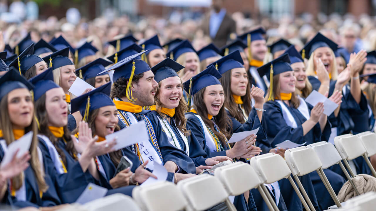 Hundreds of graduates clap and cheer from their seats