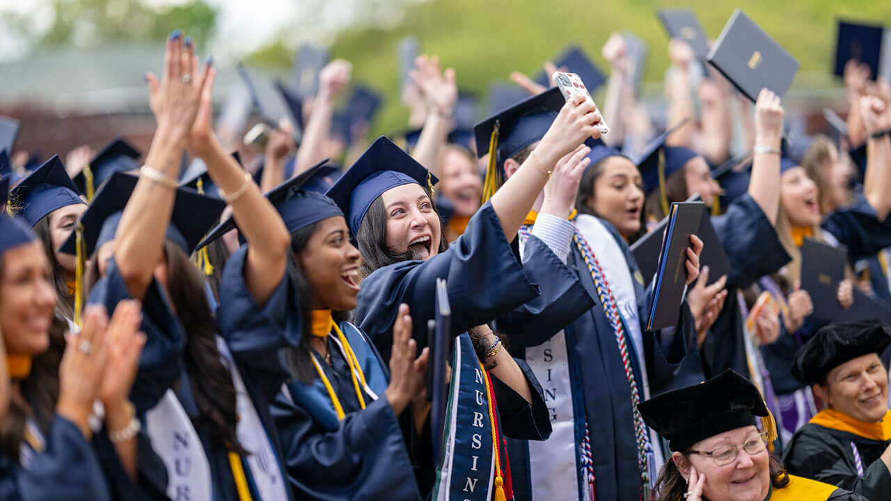 graduates cheer and take a selfie