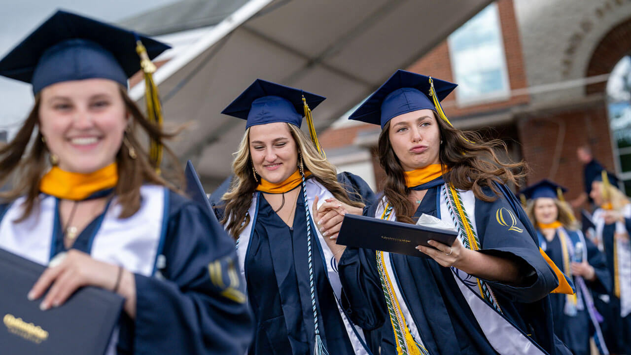 A group of graduates happily make their way back to their seats after walking across the library steps.