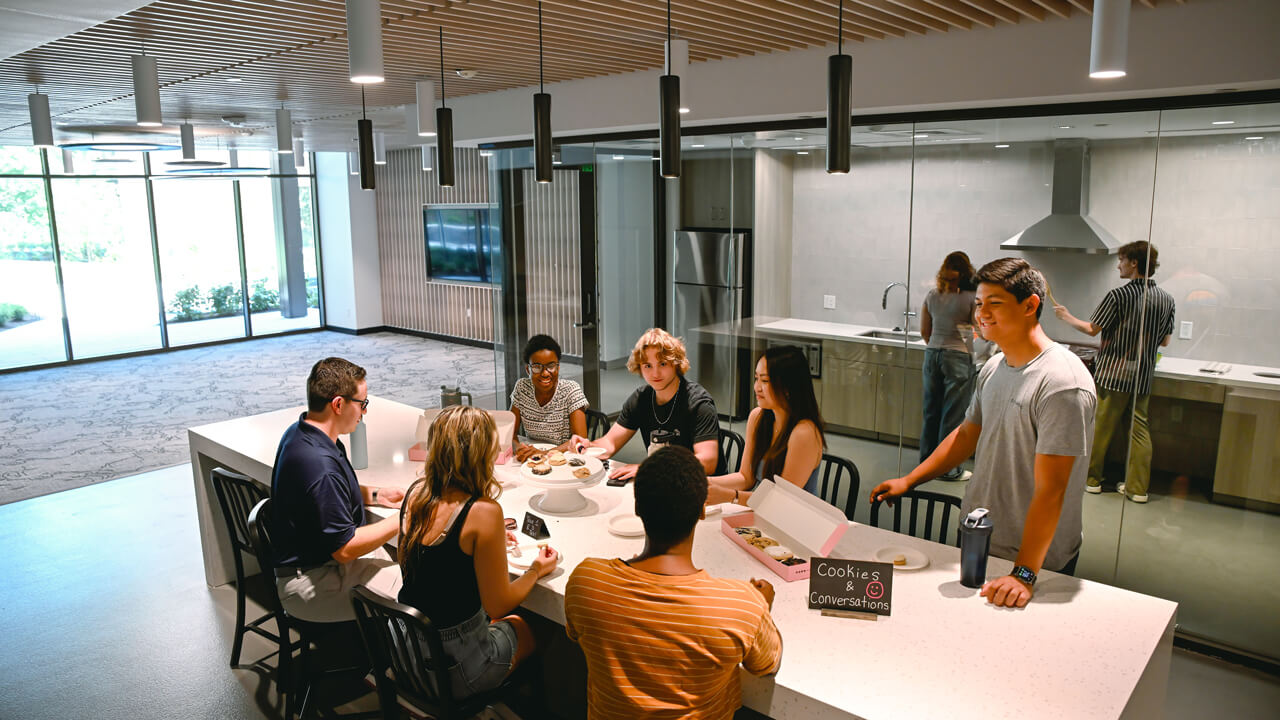 Students sit around a large table with cookies