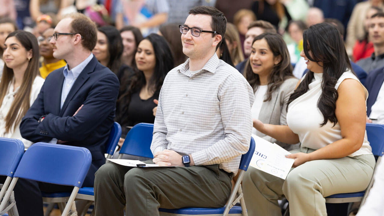 Students sit with their parents back in the audience listening to keynote speakers