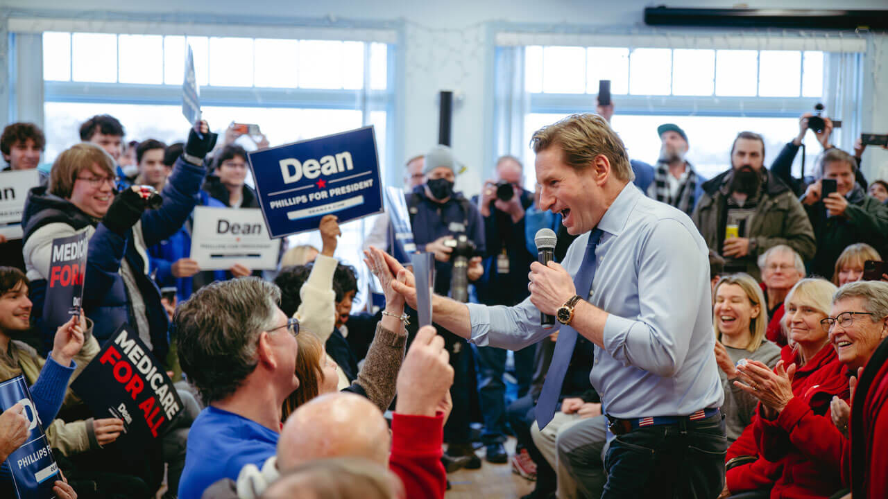 Crowd cheering and holding up signs as Dean Phillips gives a high five